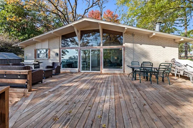 a view of a patio with table and chairs a barbeque with wooden floor and fence