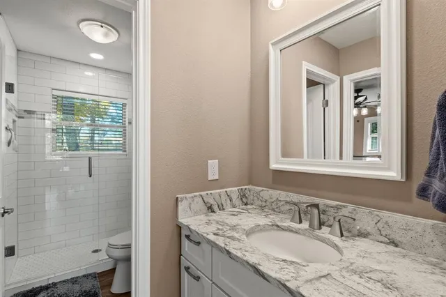 a bathroom with a granite countertop sink toilet and shower