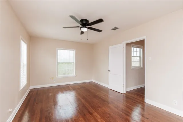 a view of empty room with wooden floor and fan