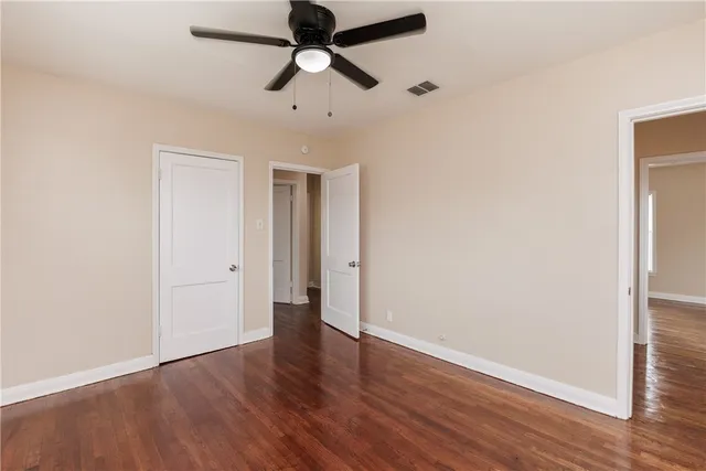 an empty room with wooden floor and ceiling fan