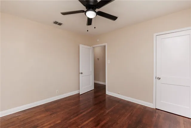 an empty room with wooden floor a ceiling fan and closet