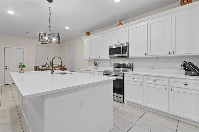 a kitchen with stainless steel appliances a sink stove and white cabinets