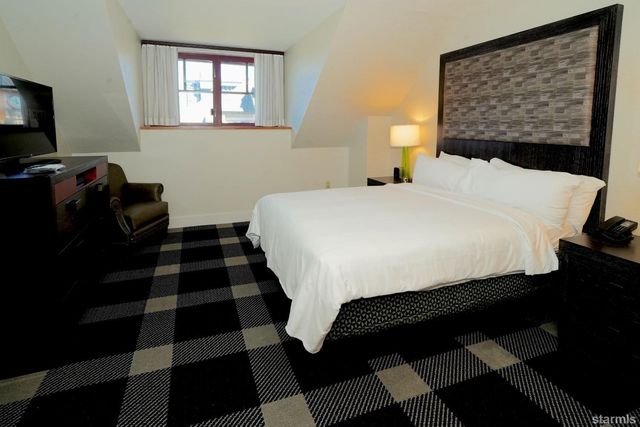 a bedroom with a bed and a lamp on dresser