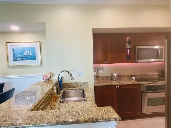 a kitchen with stainless steel appliances kitchen island granite countertop a table chairs and a sink