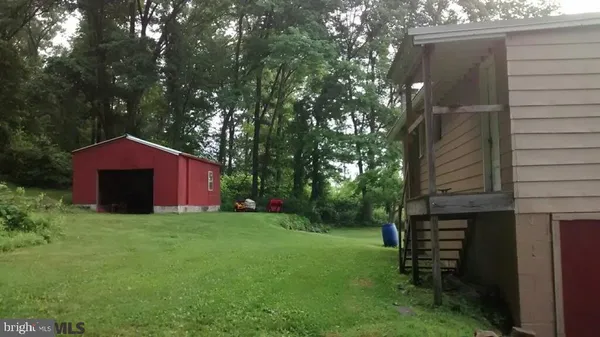 a backyard of a house with large trees and plants