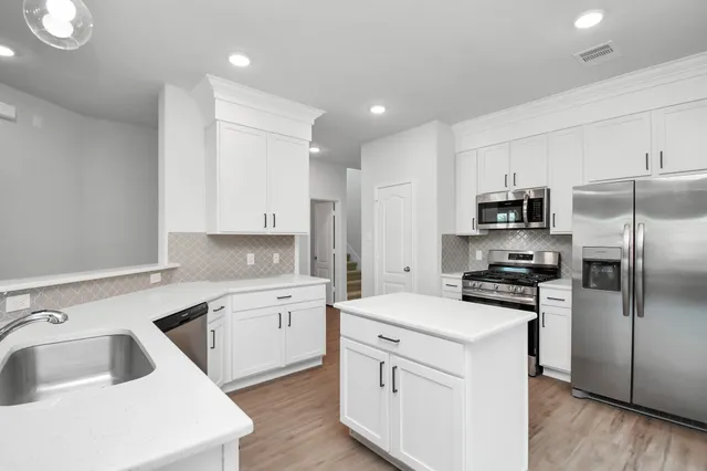 a kitchen with white cabinets sink and stainless steel appliances