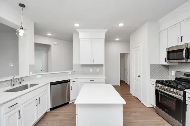 a kitchen with kitchen island a sink stainless steel appliances and cabinets