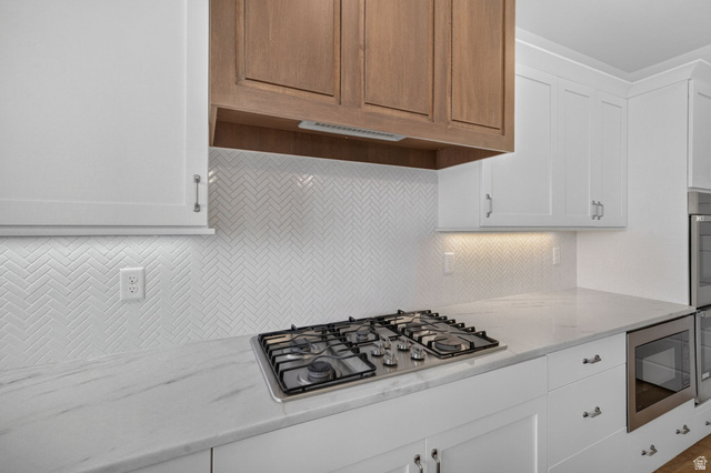 1002 West Temple Rim Lane Payson, UT 84651 - Photo 21 of 68 Gourmet kitchen featuring a built-in gas range, white shaker cabinetry, herringbone tile backsplash, and light-toned countertops