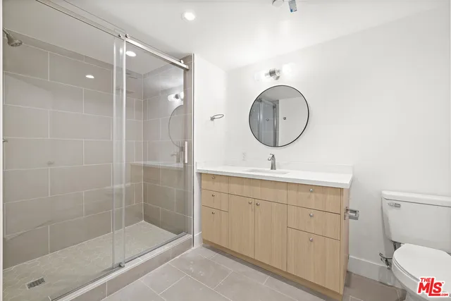 a bathroom with a toilet a sink a mirror and shower