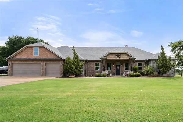a view of a house with a yard and a large tree