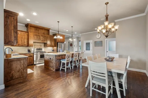 a dining room with stainless steel appliances kitchen island granite countertop a table chairs and a refrigerator