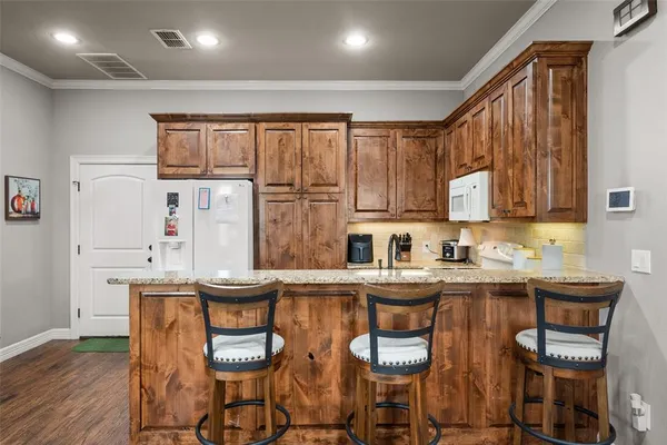 a kitchen with stainless steel appliances granite countertop a table chairs sink and cabinets