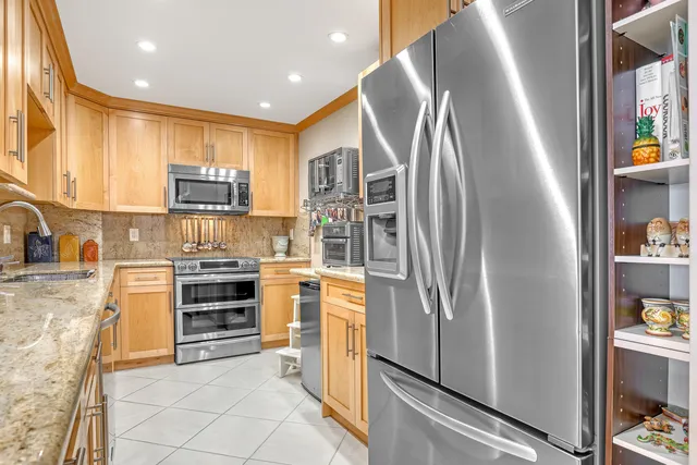 a kitchen with stainless steel appliances granite countertop a refrigerator and a stove