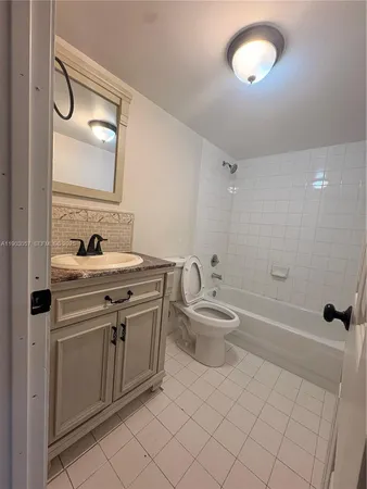 a bathroom with a granite countertop sink a toilet and shower