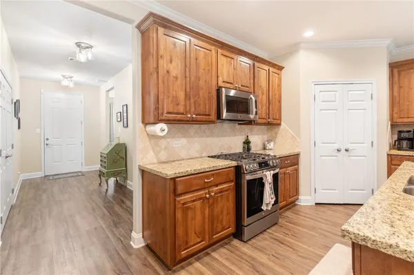 a kitchen with stainless steel appliances granite countertop a stove top oven a sink dishwasher and a refrigerator with wooden floor