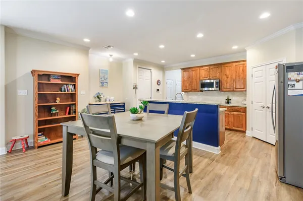 a kitchen with stainless steel appliances kitchen island granite countertop a refrigerator a stove a microwave oven a dining table and chairs with wooden floor