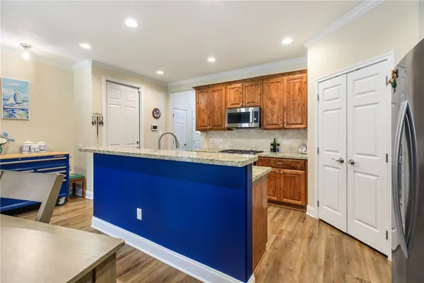 a kitchen with stainless steel appliances granite countertop a refrigerator a sink dishwasher and wooden cabinets with wooden floor