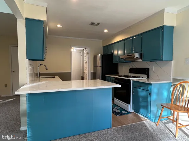 a kitchen with kitchen island stainless steel appliances a sink stove and refrigerator