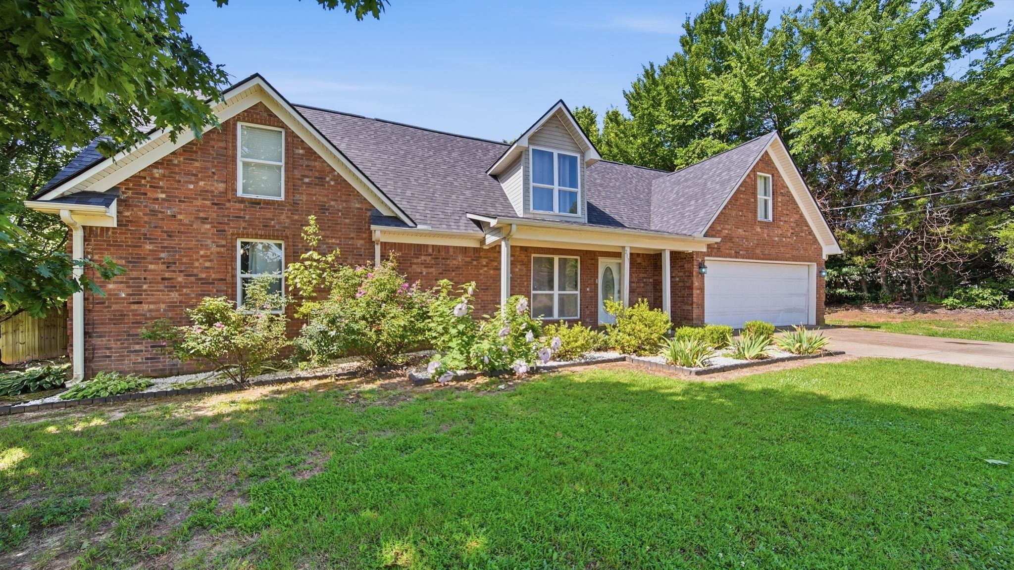 217 Rae Drive Munford, TN 38058 - Photo 2 of 40 Brick residence featuring a covered front porch, white garage door, and dormer windows