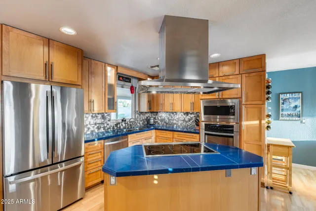 a kitchen with stainless steel appliances granite countertop a sink a stove and a wooden floors