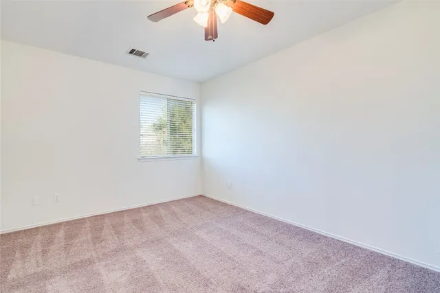 an empty room with a window and a ceiling fan