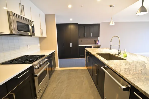 a kitchen with stainless steel appliances granite countertop a sink a stove and a refrigerator