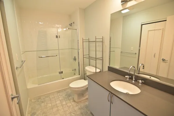 a bathroom with a granite countertop sink toilet mirror and shower