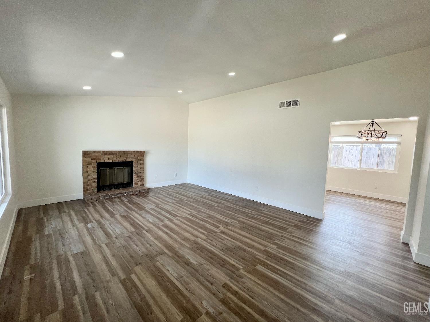 Undisclosed Address Bakersfield, CA 93308 - Photo 3 of 23 an empty room with wooden floor and fireplace