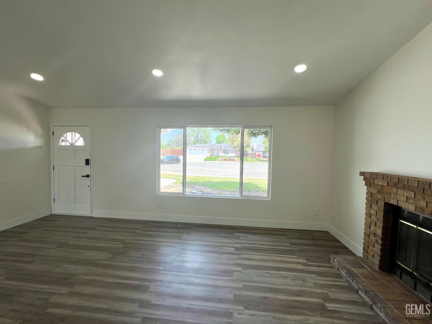 Undisclosed Address Bakersfield, CA 93308 - Photo 6 of 23 an empty room with wooden floor and a fireplace