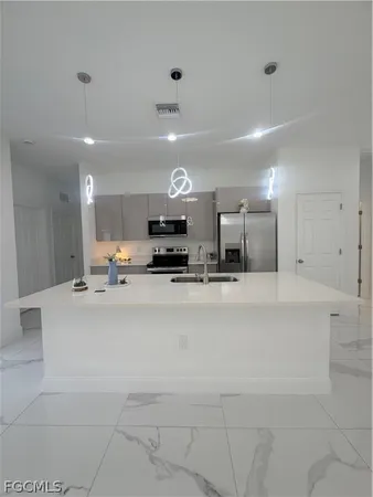 a large white kitchen with kitchen island a sink a stove and a refrigerator