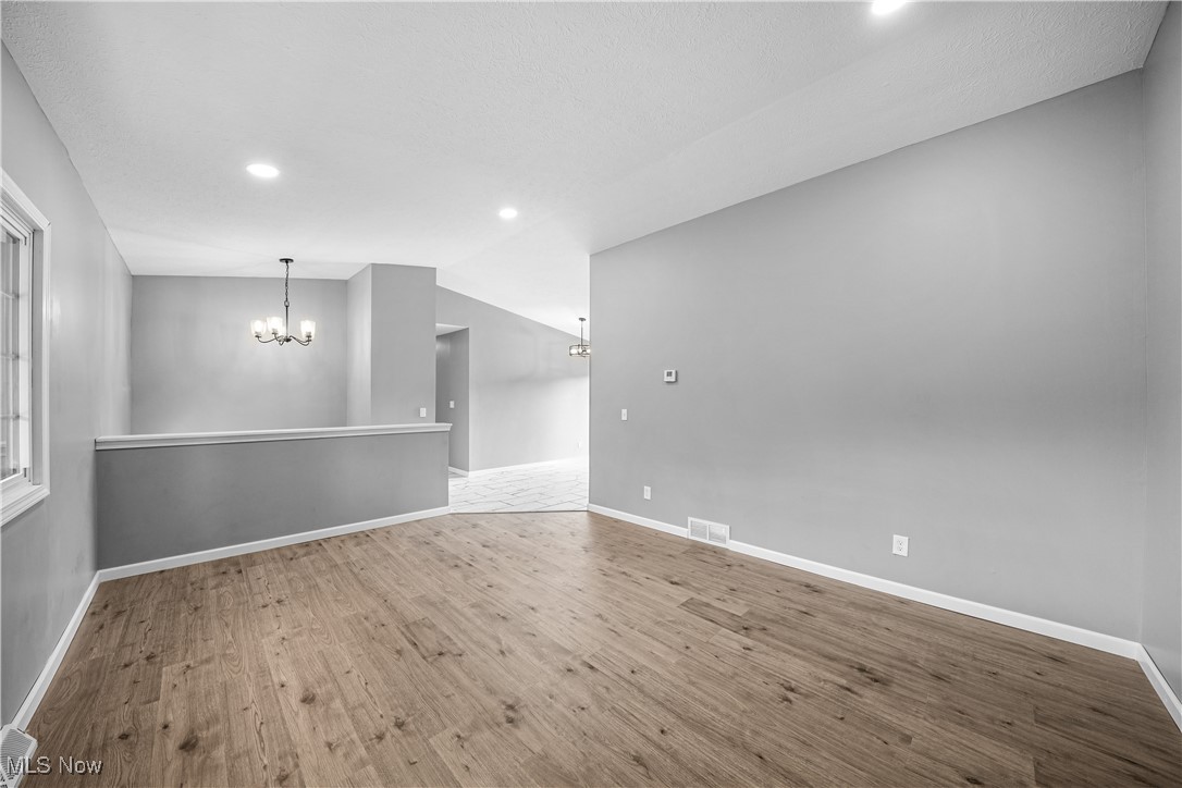 23595 Sandy Creek Road Minerva, OH 44657 - Photo 7 of 32 Spare room with a chandelier, wood finished floors, recessed lighting, baseboards, and lofted ceiling