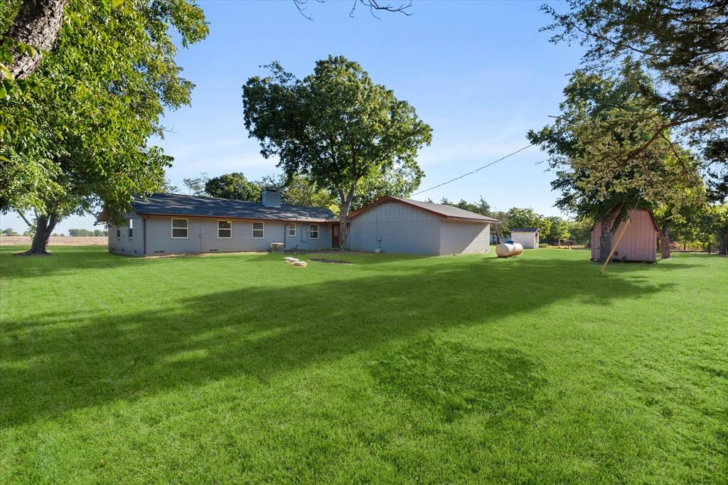 917 Goodwyn Road Italy, TX 76651 - Photo 27 of 40 Expansive lawn with mature trees, detached secondary structure, and an additional shed