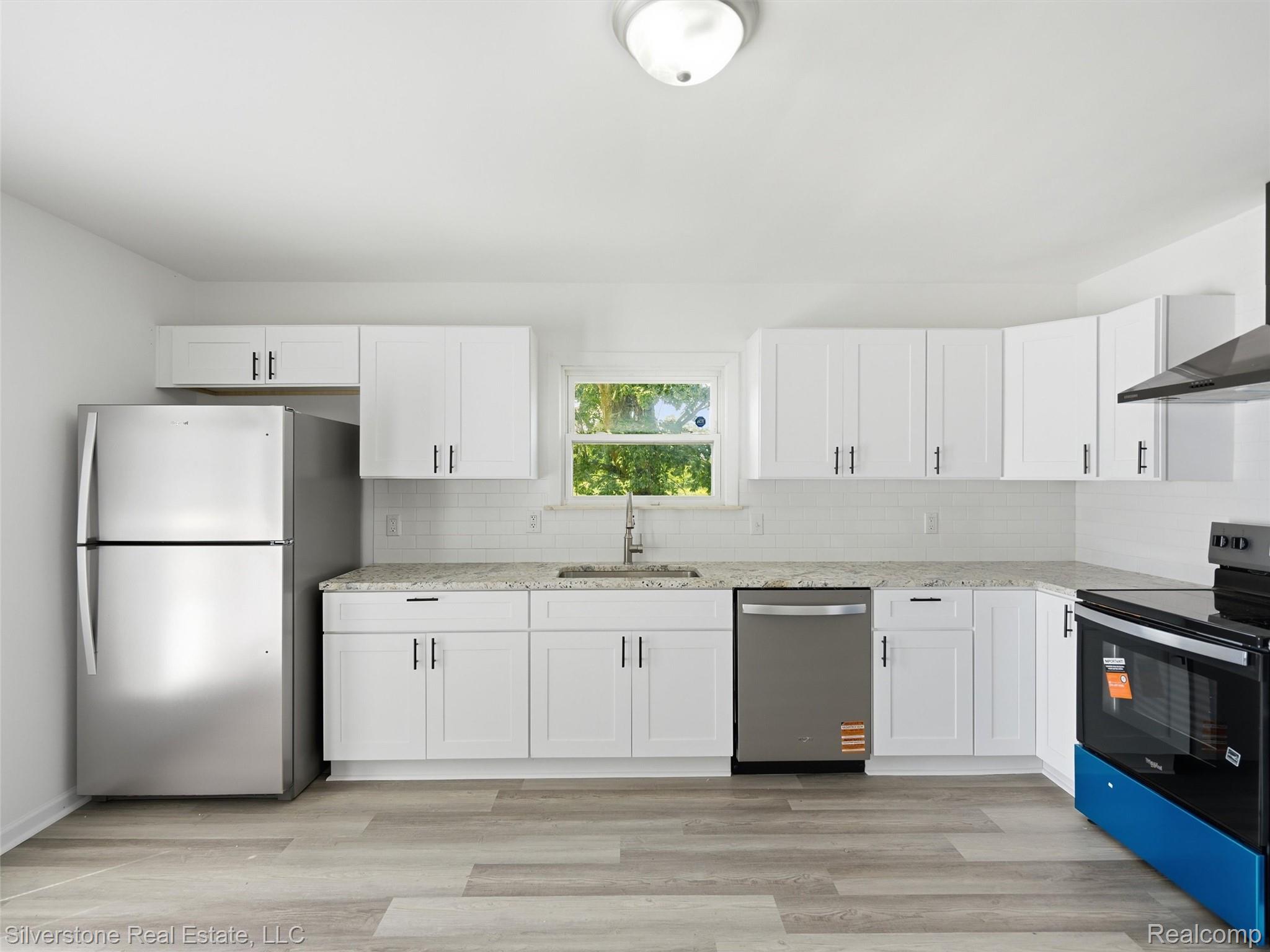 9691 Grames Road Maybee, MI 48159 - Photo 24 of 44 Kitchen featuring white cabinetry, stainless steel appliances, light-toned countertops, white subway tile backsplash, and wood-finish flooring