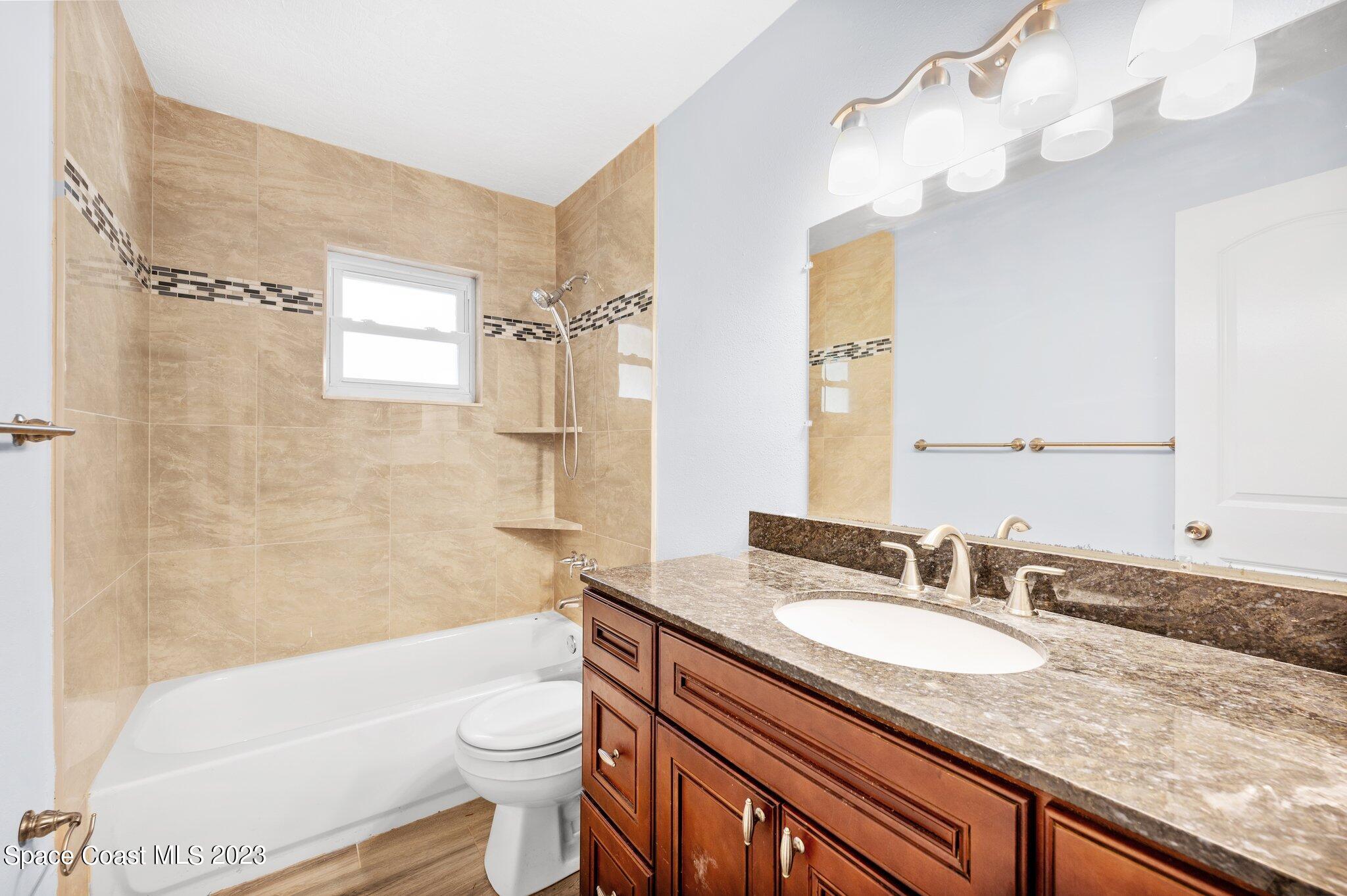 3030 Hield Road Melbourne, FL 32904 - Photo 14 of 36 a bathroom with a granite countertop sink toilet mirror and a bathtub
