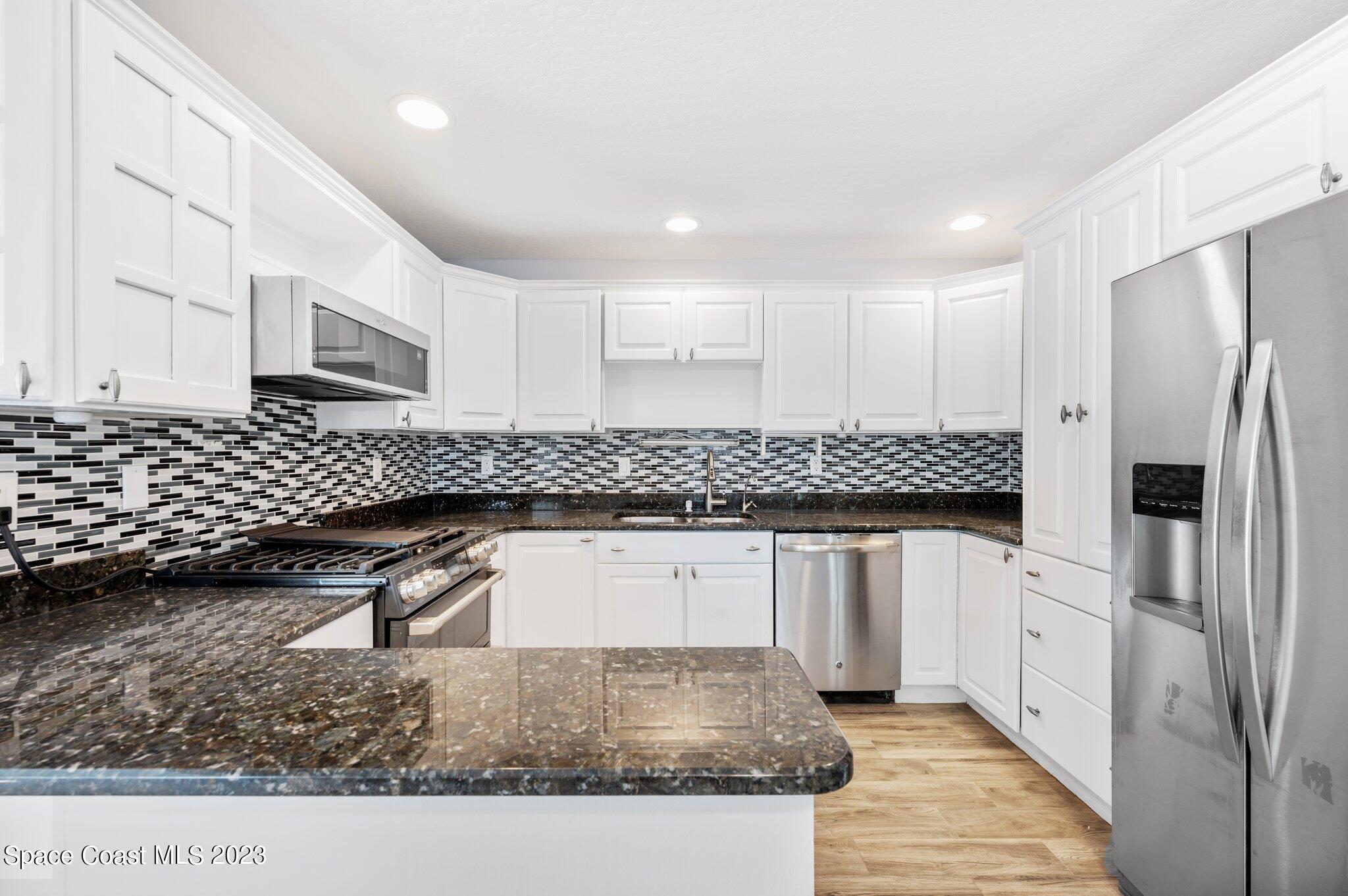 3030 Hield Road Melbourne, FL 32904 - Photo 29 of 36 a kitchen with stainless steel appliances granite countertop a sink stove and refrigerator