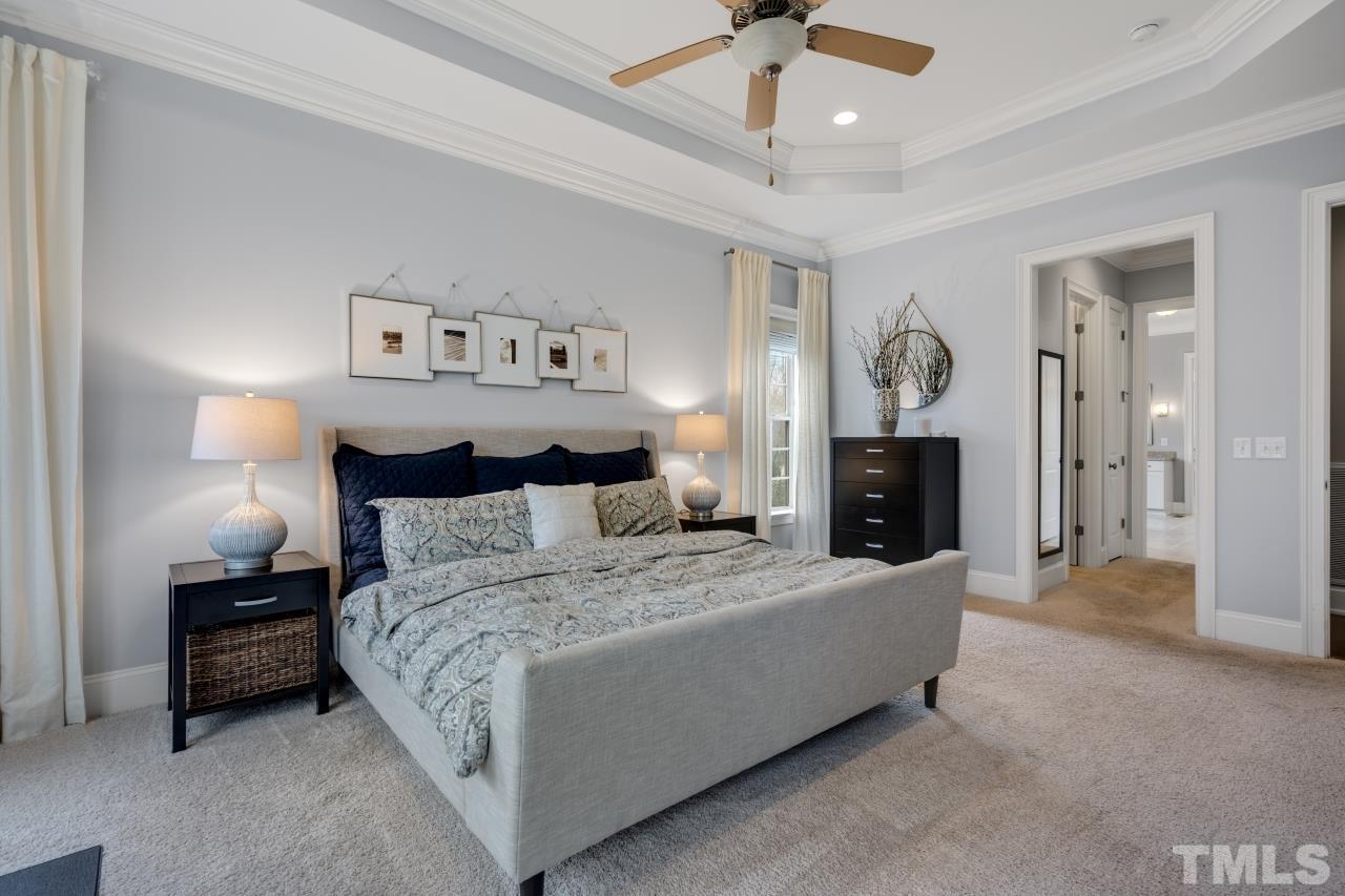 12212 Kyle Abbey Lane Raleigh, NC 27613 - Photo 17 of 30 a spacious bedroom with a bed and a chandelier