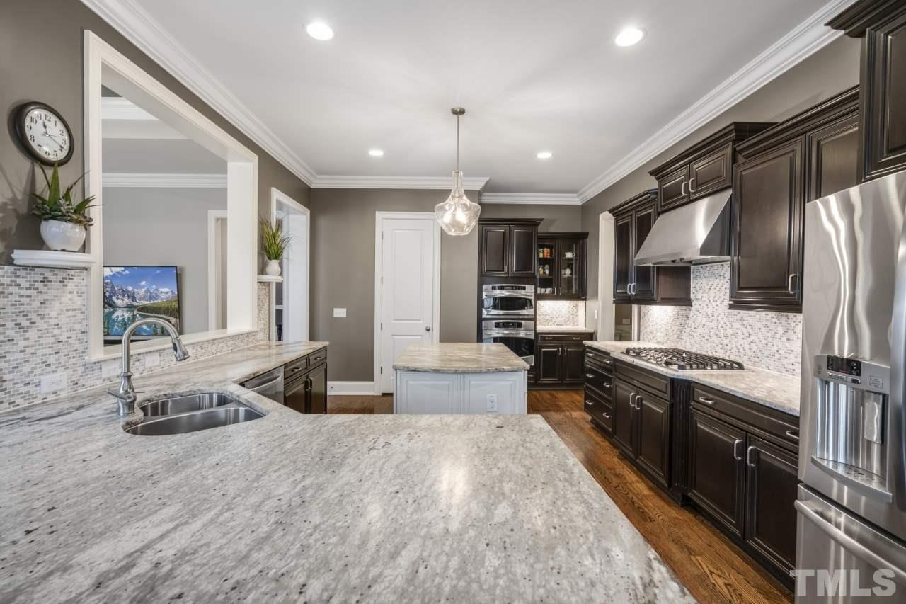 12212 Kyle Abbey Lane Raleigh, NC 27613 - Photo 9 of 30 a kitchen with stainless steel appliances granite countertop a sink stove and refrigerator