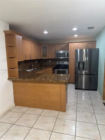 a kitchen with granite countertop a refrigerator and a cabinets