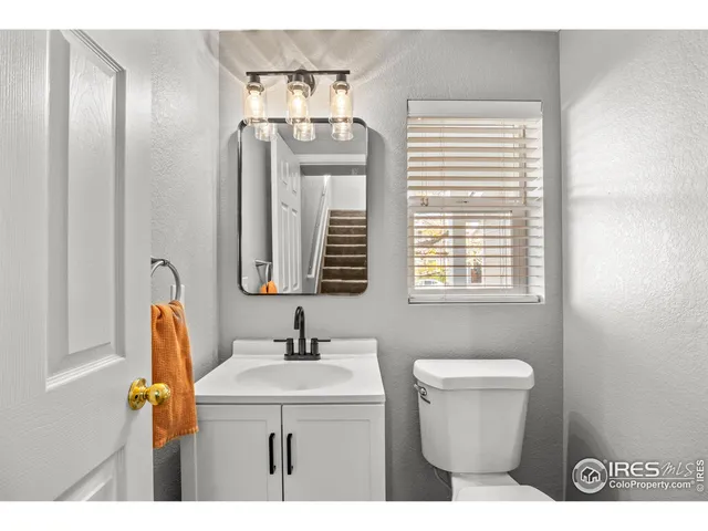 a bathroom with a sink a mirror a toilet and a window