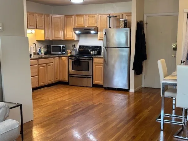 a kitchen with granite countertop a refrigerator stove and wooden floor