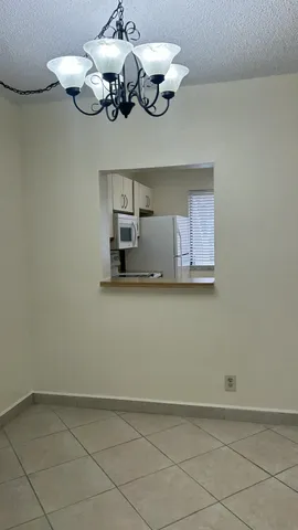 a view of a room with a chandelier fan and kitchen view
