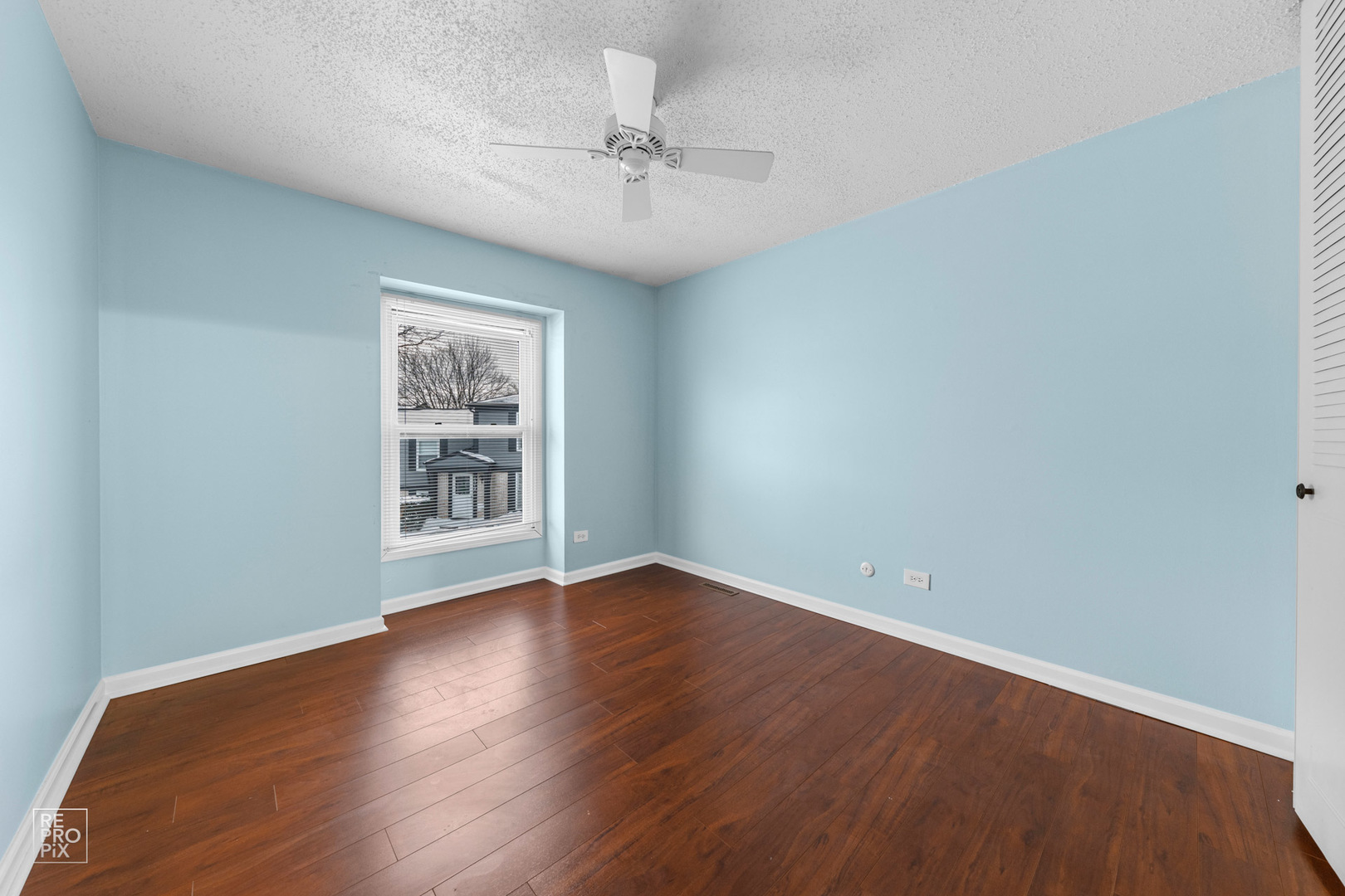 1306 Inverrary Lane, Unit 1306 Deerfield, IL 60015 - Photo 9 of 12 an empty room with wooden floor chandelier fan and windows