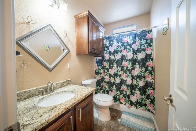 a bathroom with a granite countertop sink a toilet and a mirror