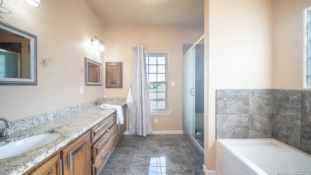 a bathroom with a granite countertop tub sink a mirror and a shower