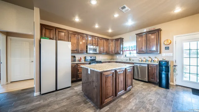 a kitchen with stainless steel appliances granite countertop a refrigerator and a stove top oven