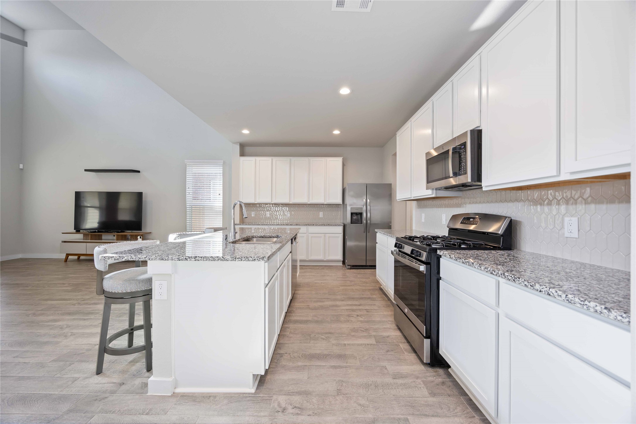 15038 Timberson Rdg Lane Houston, TX 77090 - Photo 11 of 29 a large kitchen with stainless steel appliances granite countertop a stove top oven a sink a refrigerator and white cabinets