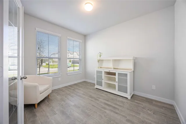 a view of an empty room with a window and wooden floor