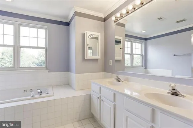 a bathroom with a tub a sink double vanity and window