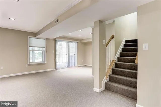 a view of an empty room with stairs and windows