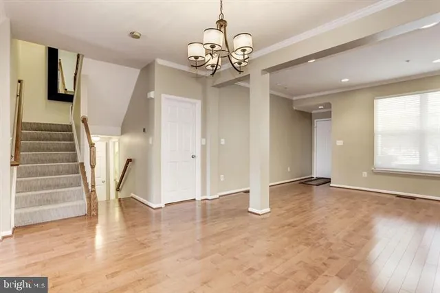 a view of an empty room with wooden floor and windows